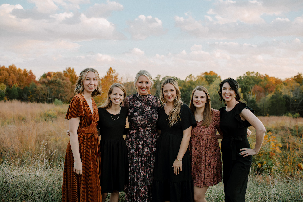 Six Scarlet Hope team members standing arm in arm in a golden field